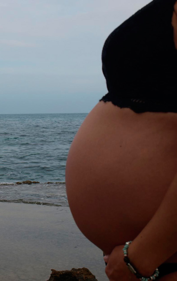 Mujer embarazada en el mar al atardecer.