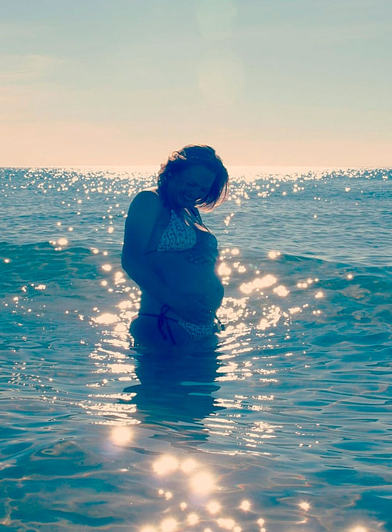 Mujer embarazada en el mar al atardecer.